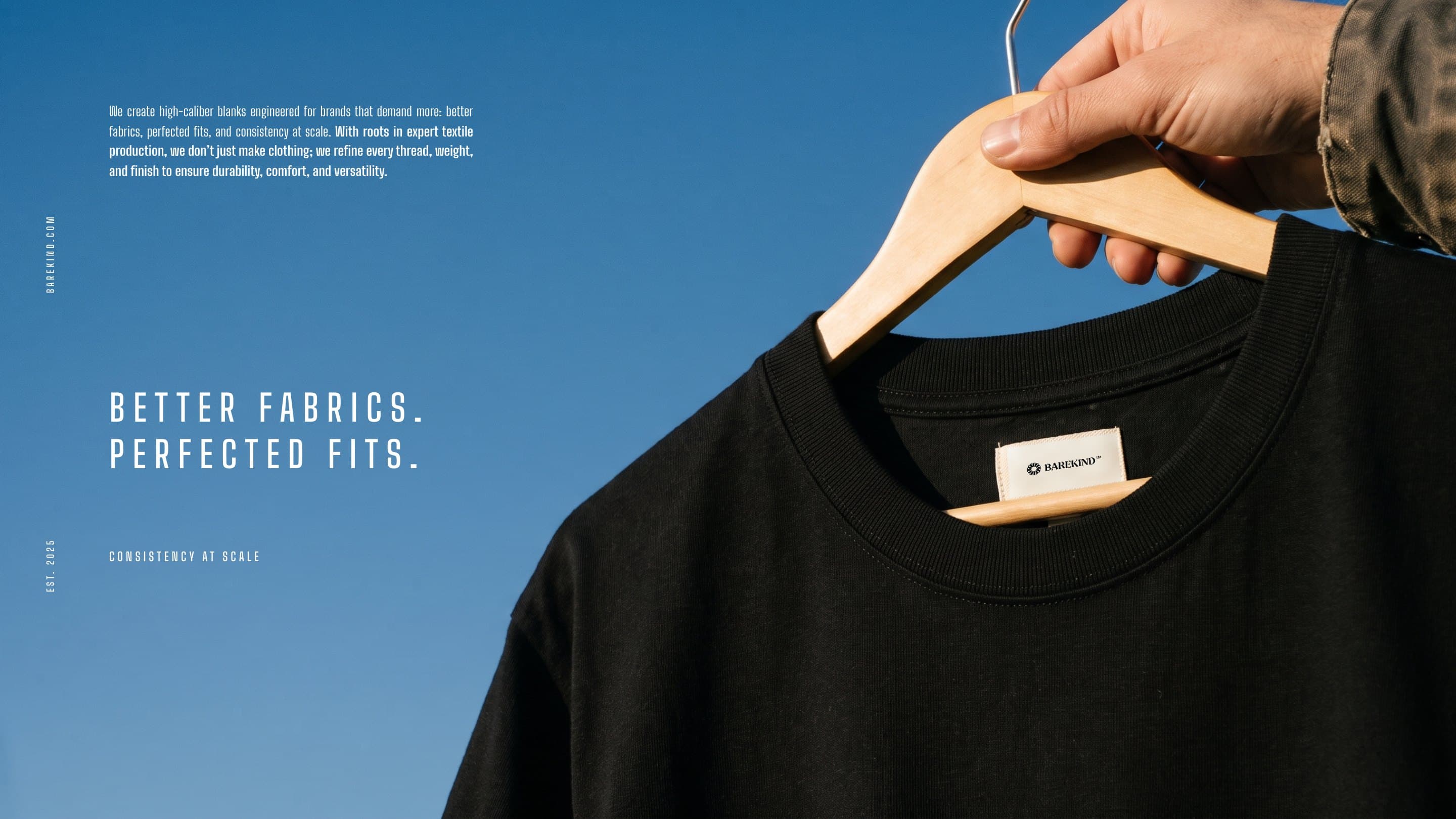 An onyx Barekind blank on its hanger against a blue sky, its woven label: Better fabrics. Perfected fits.