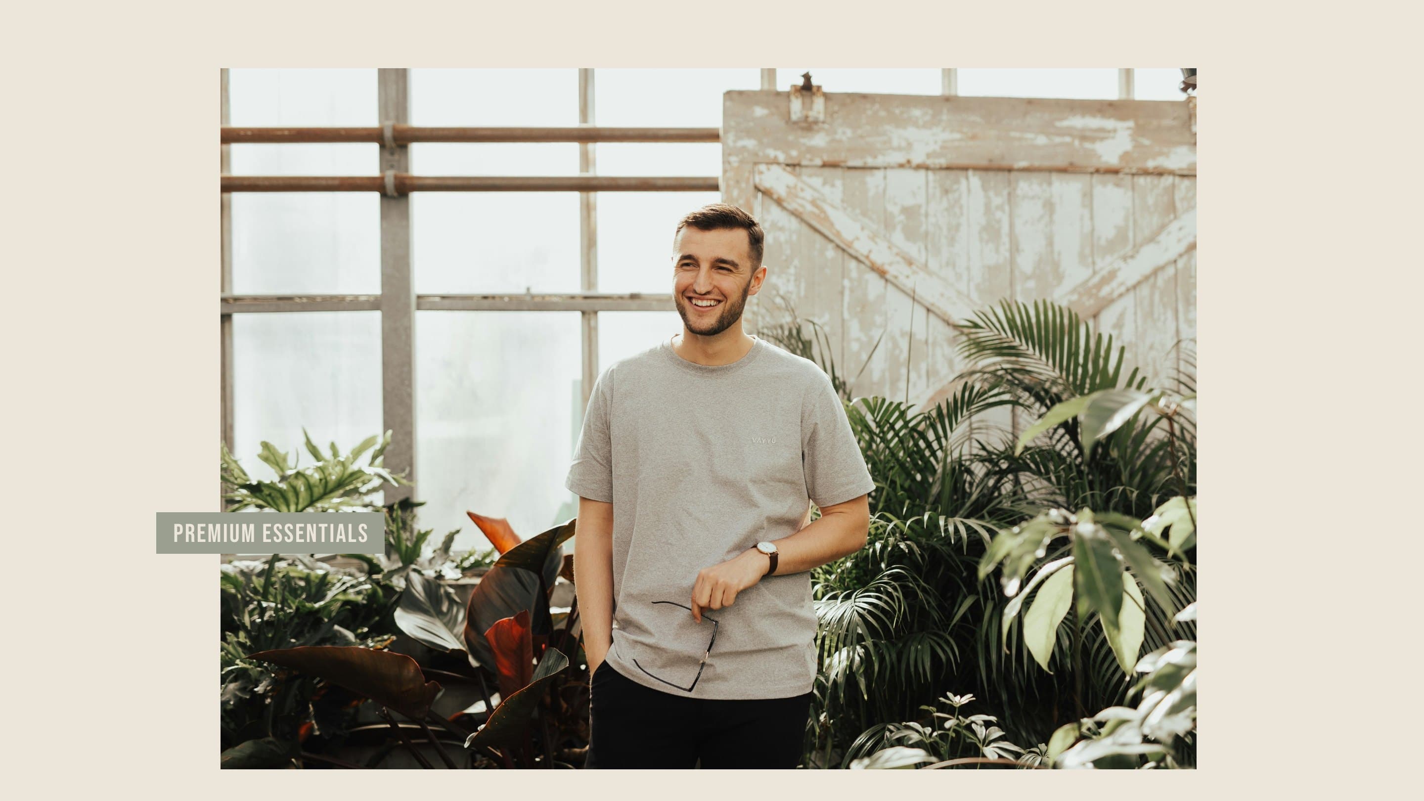 A man in a plain grey tee in a greenhouse, the tab Premium essentials laid across