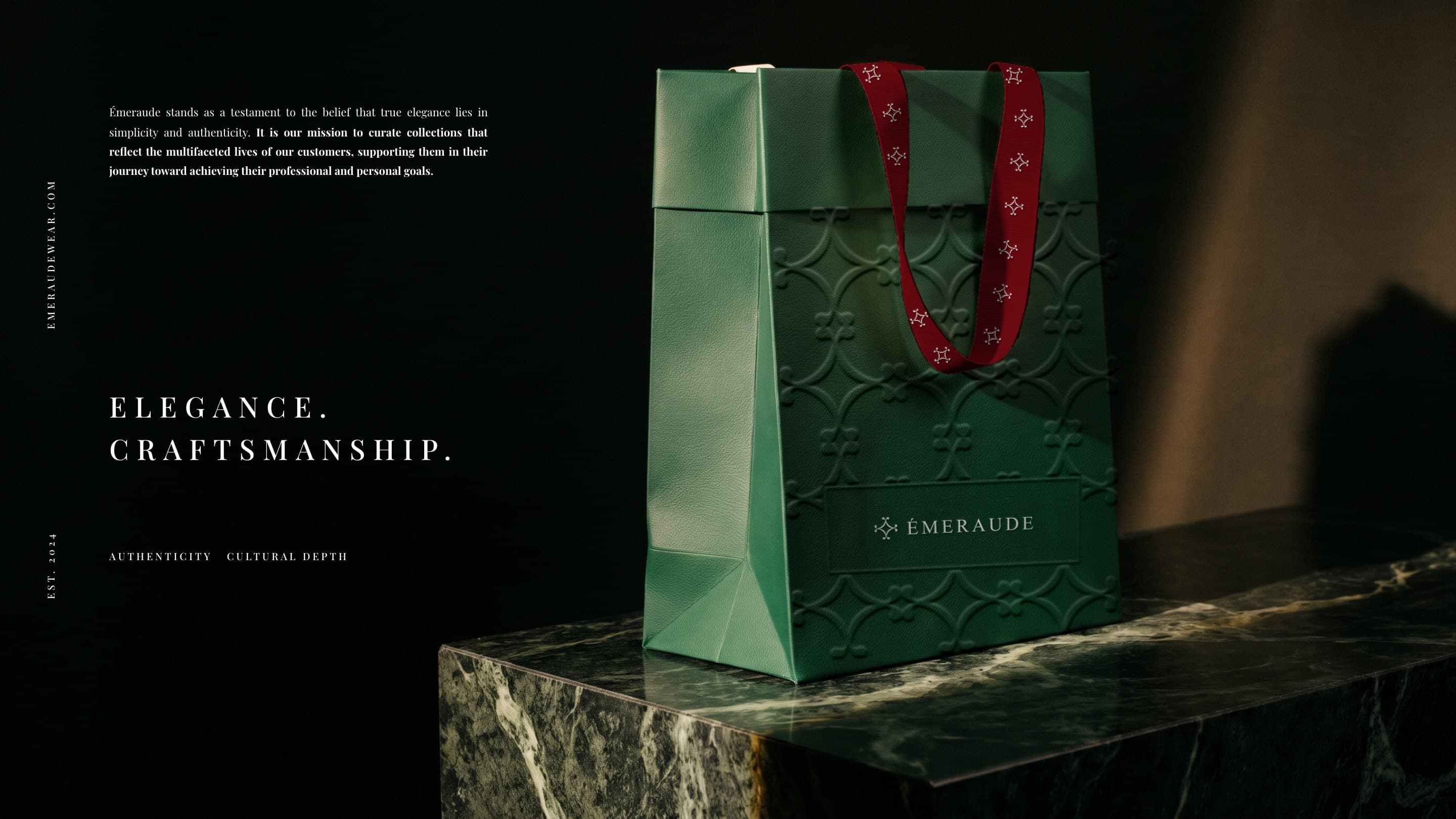 A green Émeraude bag with ivory grosgrain handles and the lockup foil-stamped in silver on a block of green marble in a shaft of light, beside the brand's mission: Elegance. Craftsmanship.