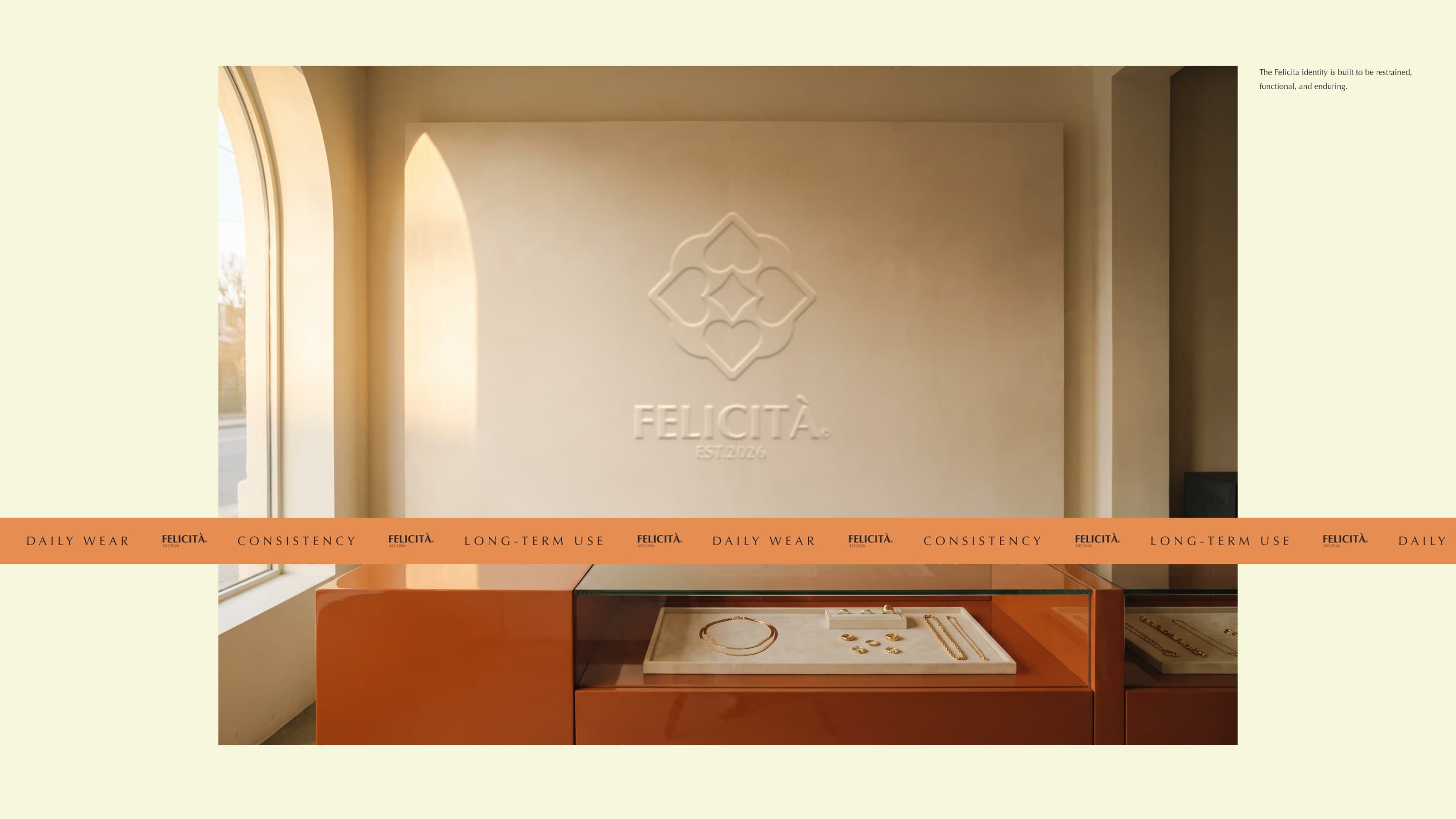 The Felicità boutique, the emblem and wordmark in relief on its ivory plaster wall above a warm-gold display counter, the band of Daily wear, Consistency and Long-term use across it
