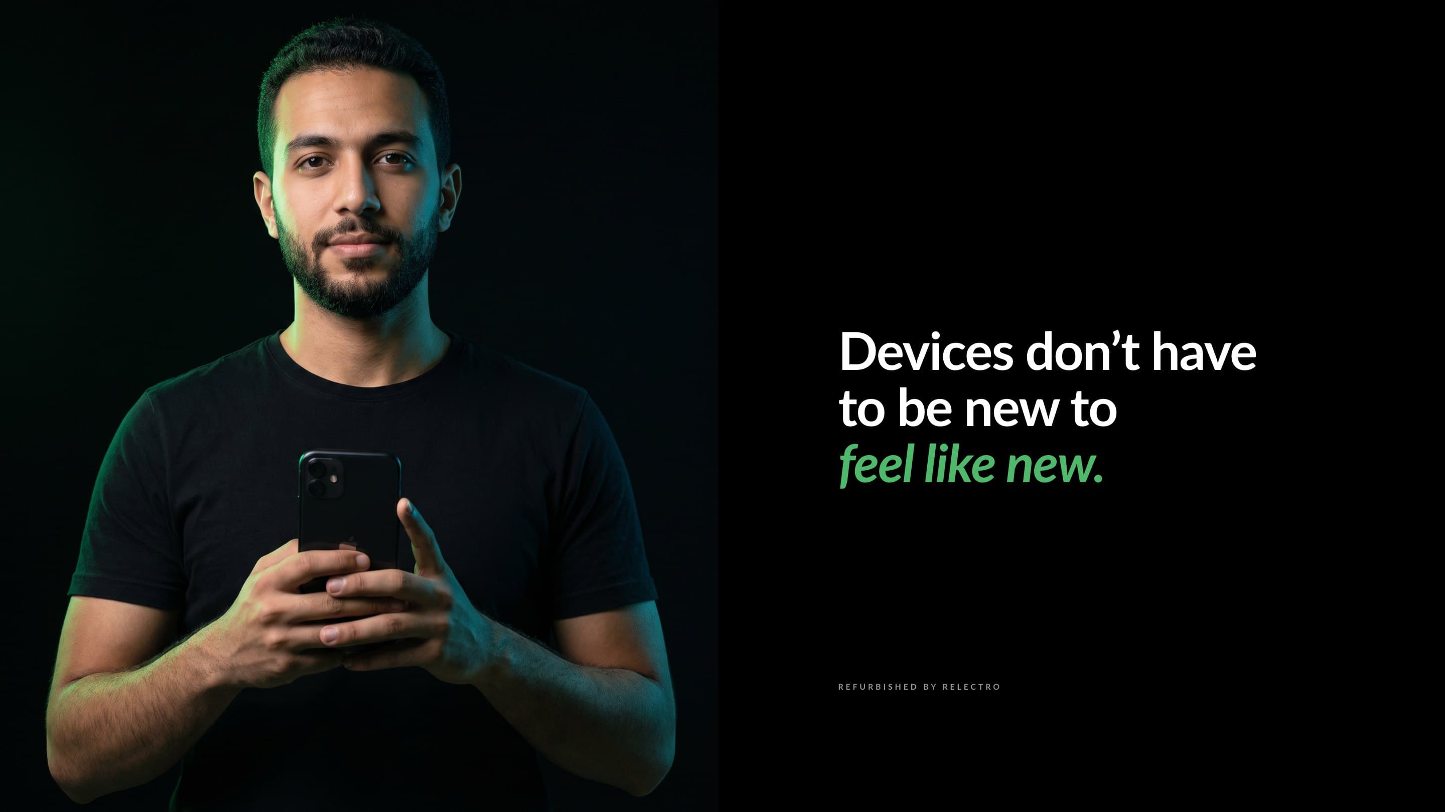 A man holding his phone, lit in green on black, beside Devices don’t have to be new to feel like new.