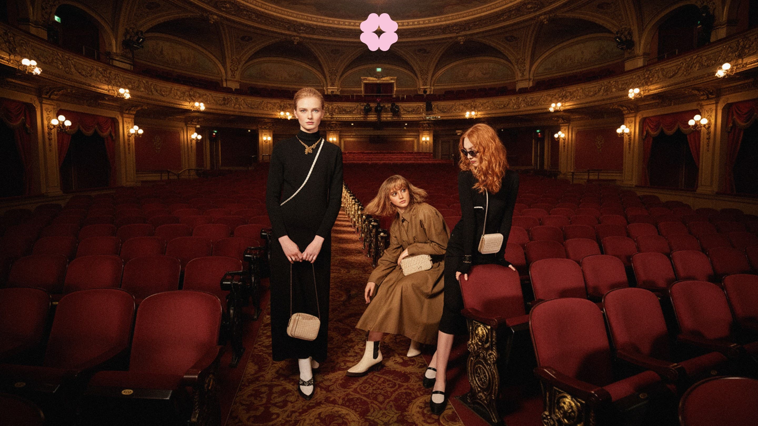 Three women in black and camel in a red velvet theatre, the Shishis flower up in the dark of the ceiling