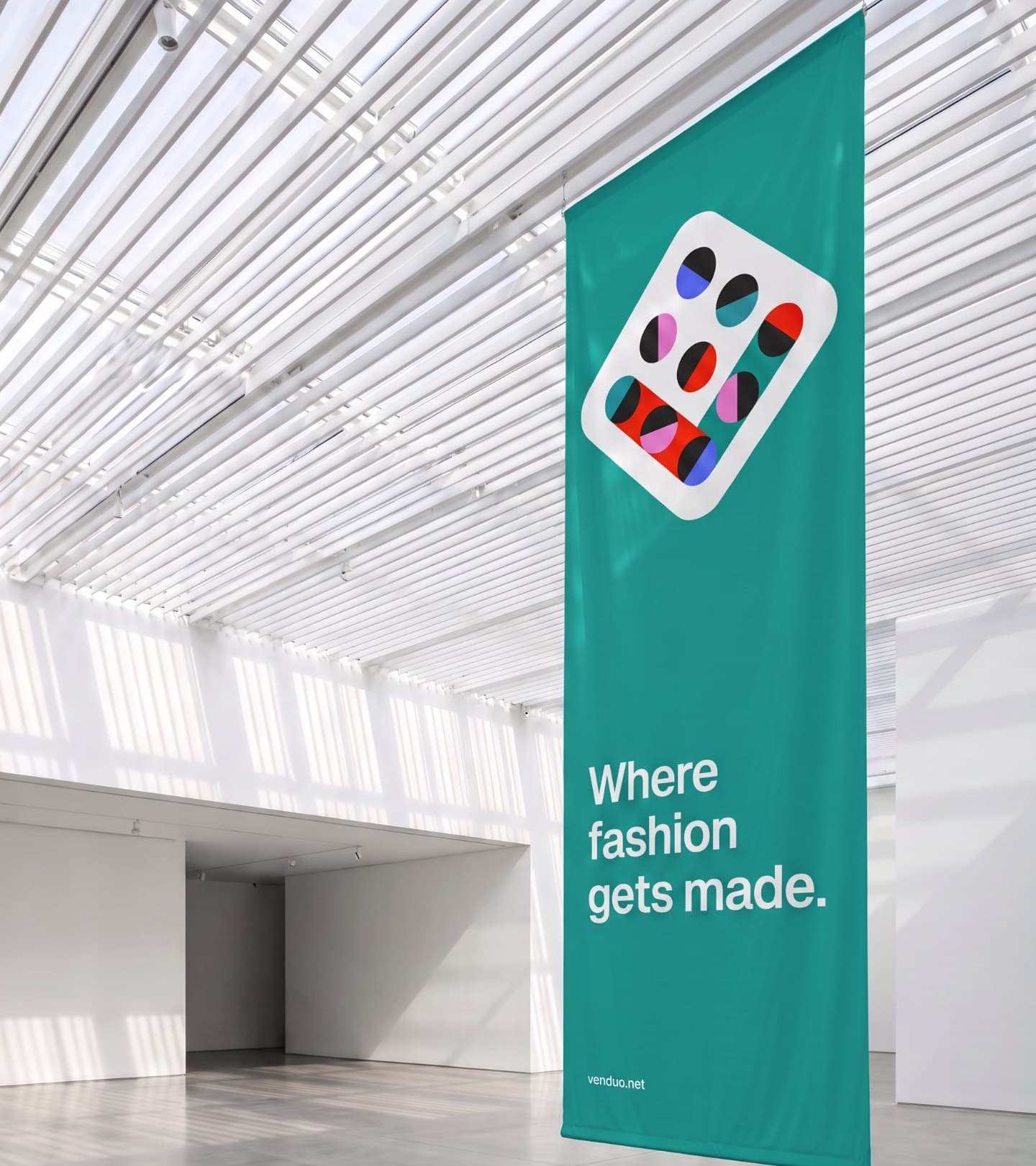 A teal Venduo banner hanging in a glass atrium: Where fashion gets made.
