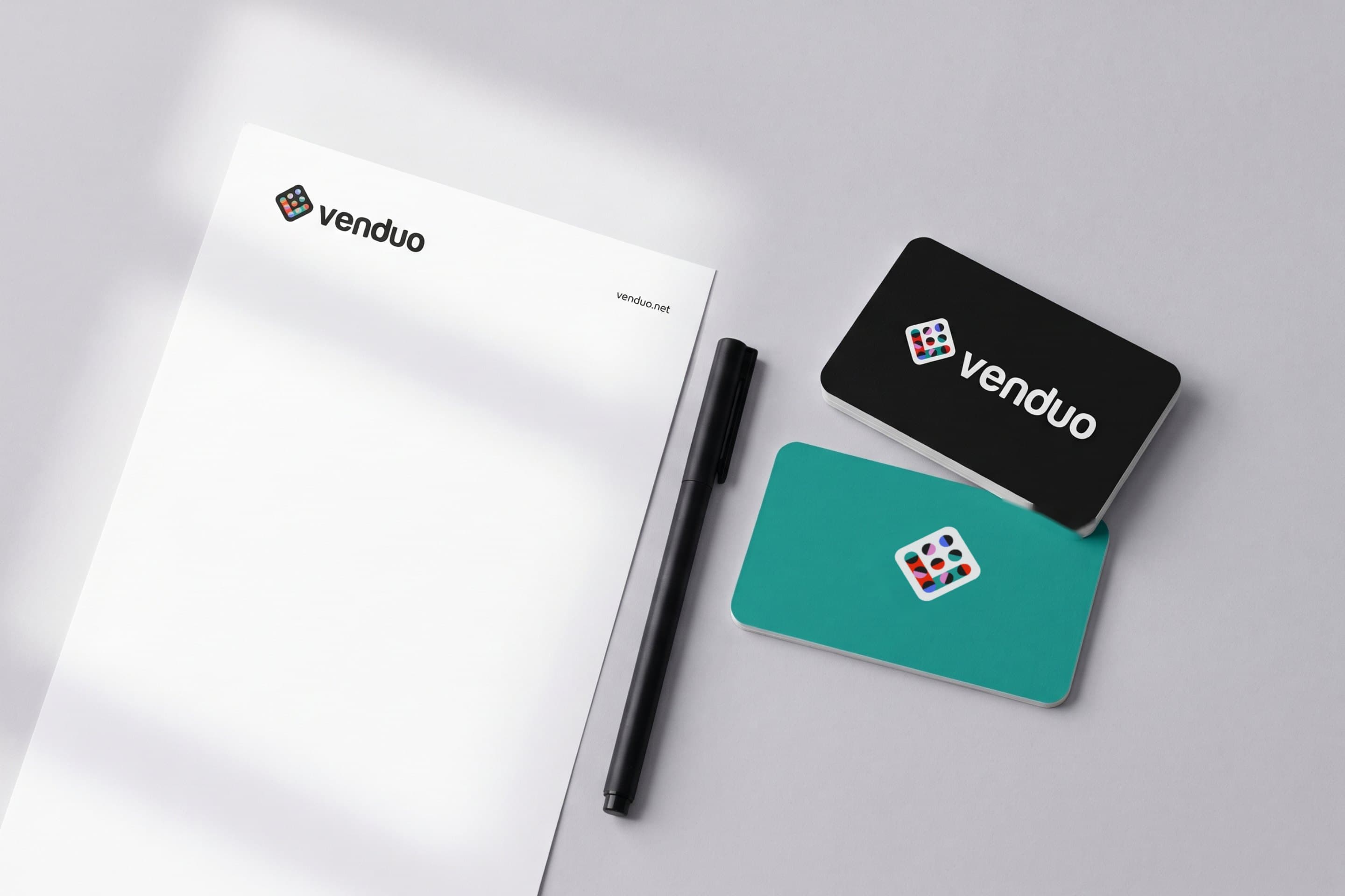 Venduo letterhead, a black and a teal business card, and a pen