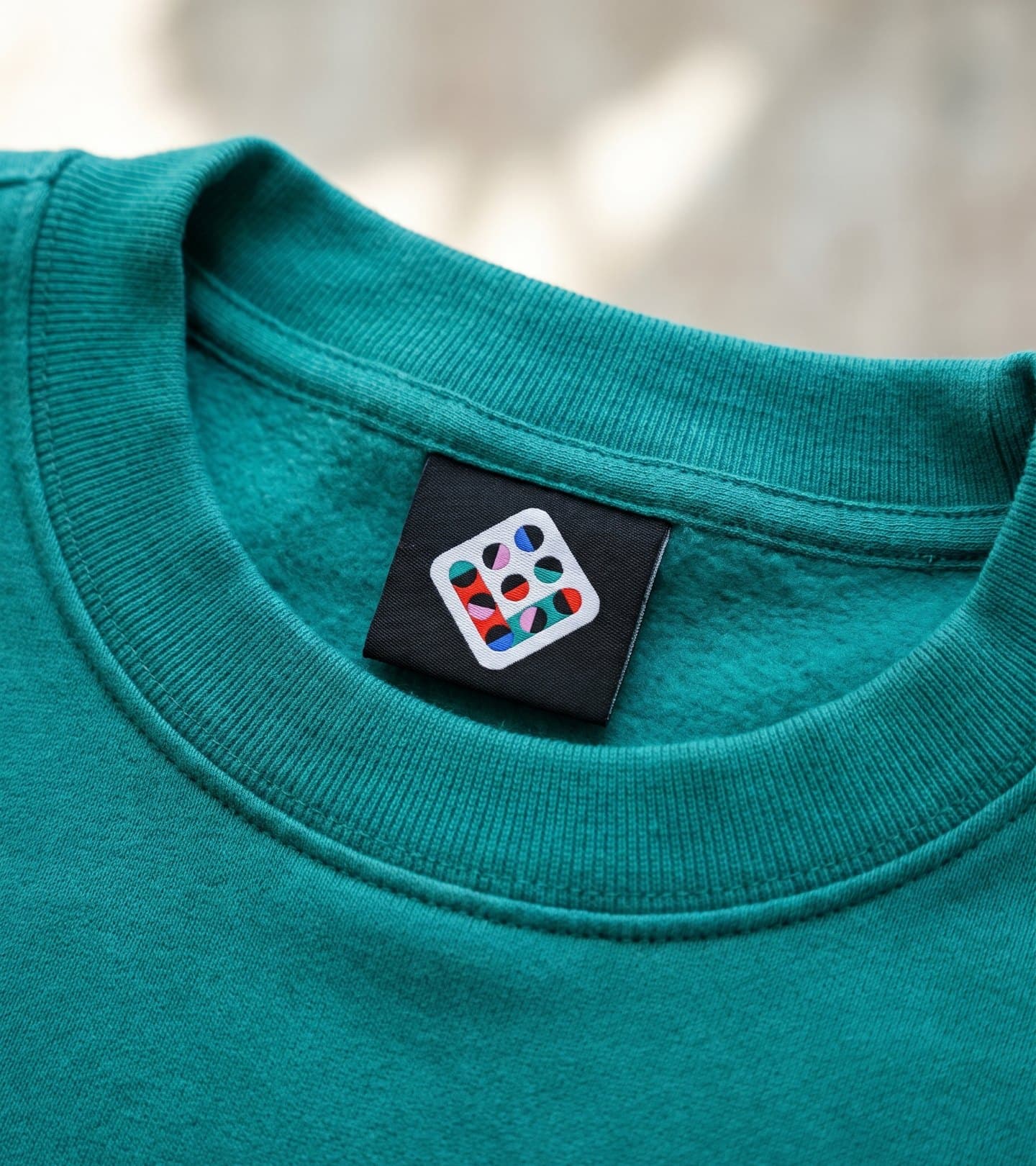 The mark woven on a black label inside a teal sweatshirt collar