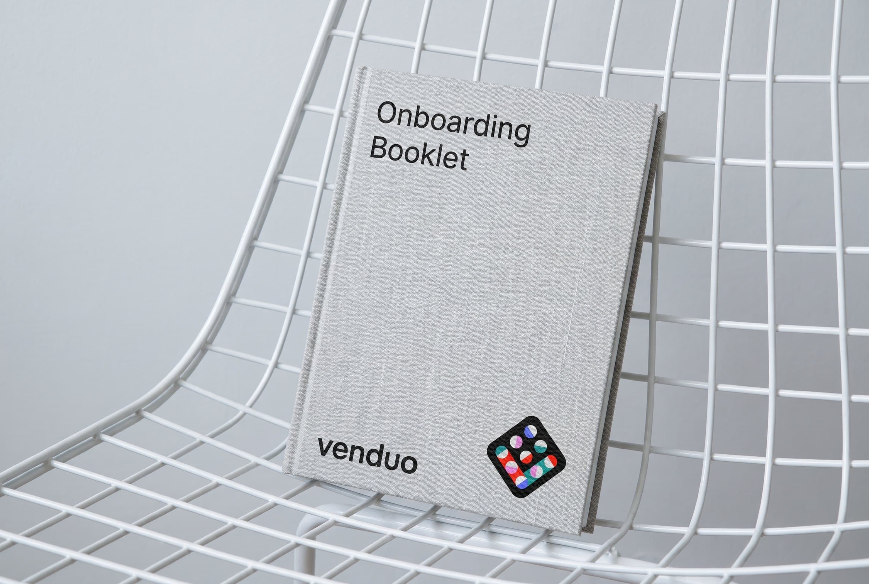 The Venduo onboarding booklet on a white wire chair